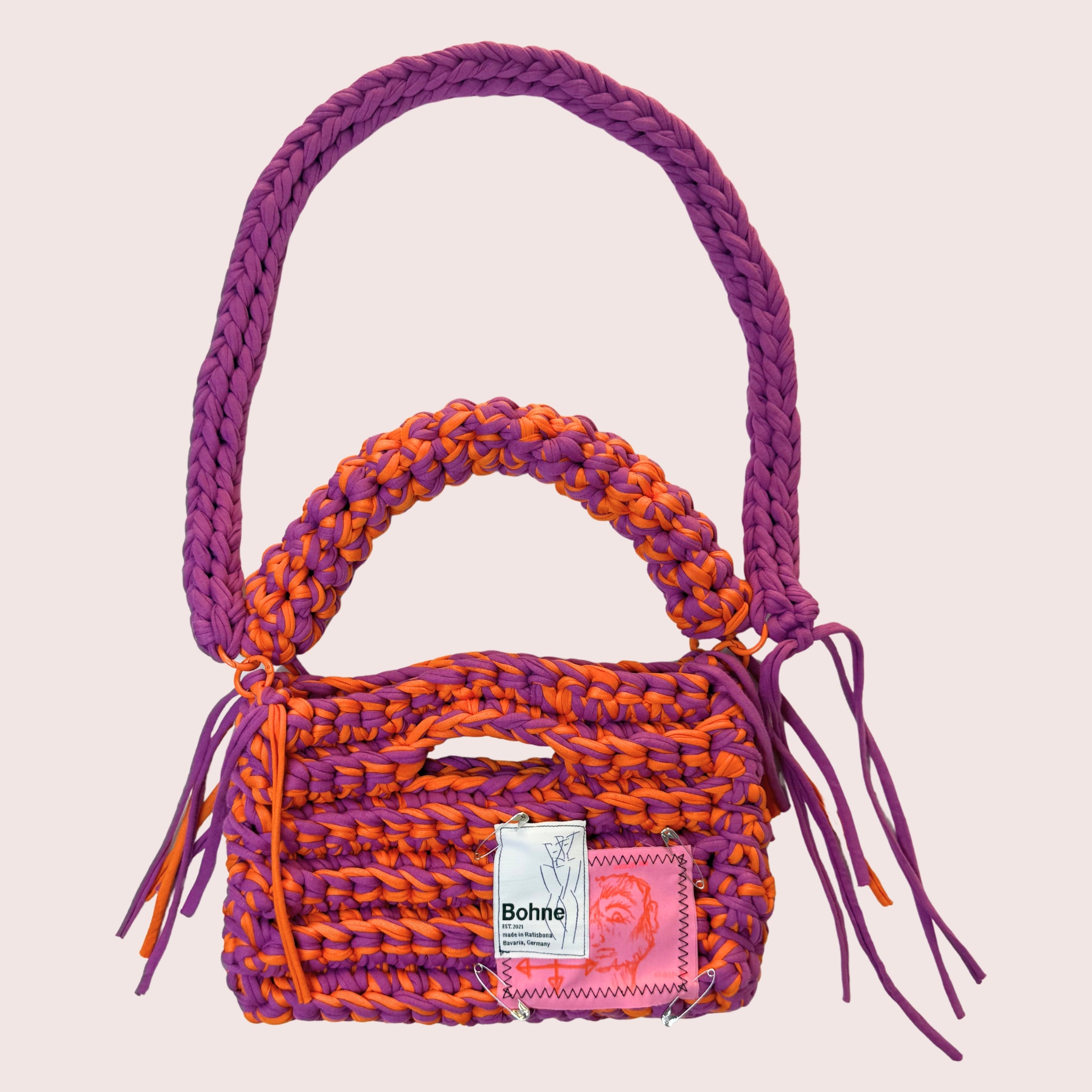 gehäkelte Schultertasche mit handbemalten Bild aus recyceltem T-Shirt Garn in lila orange freigestellt